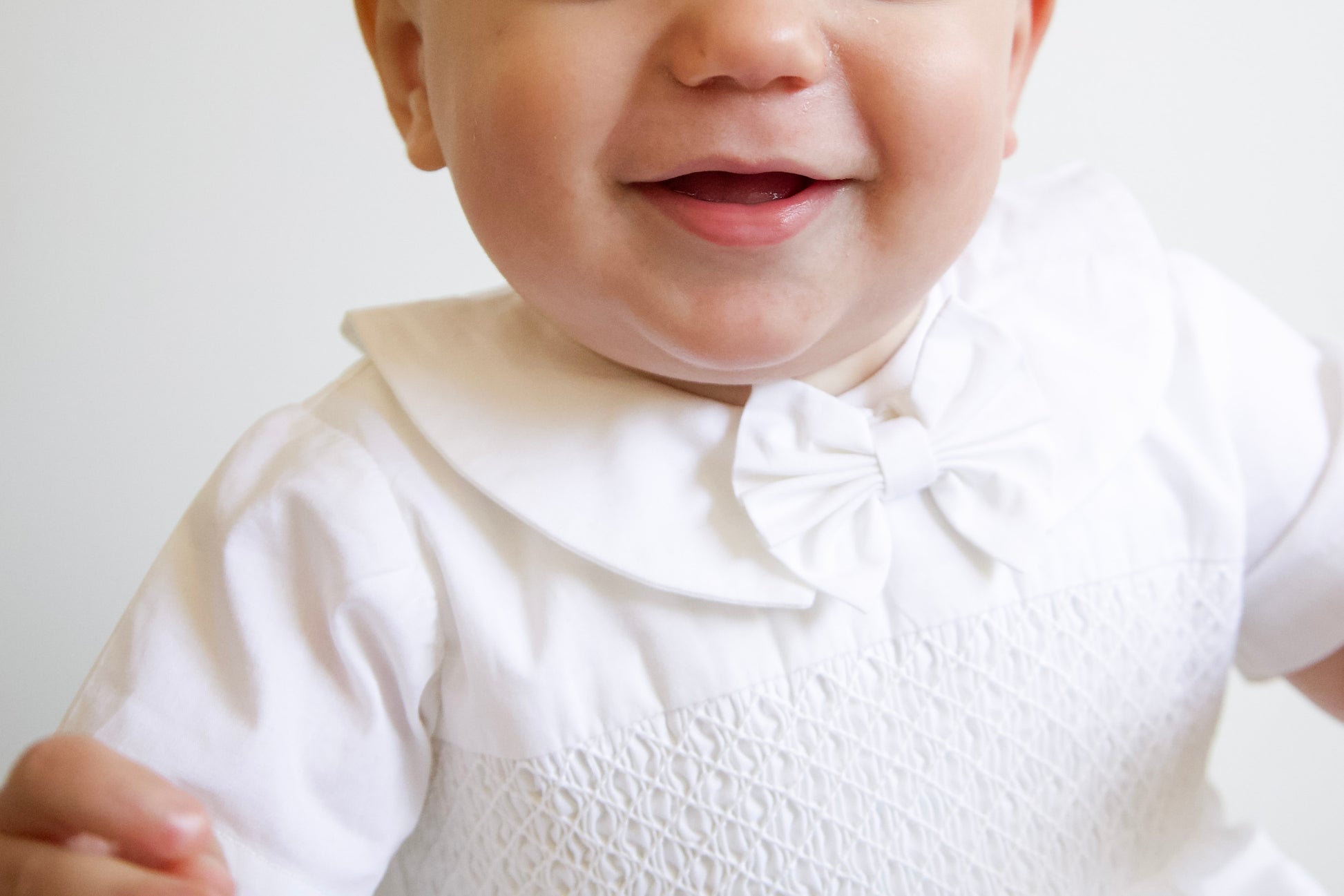 Baby wearing a white outfit with a bow